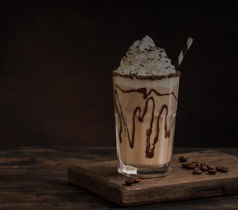 Iced coffee cocktail or frappe with ice cubes and cream in